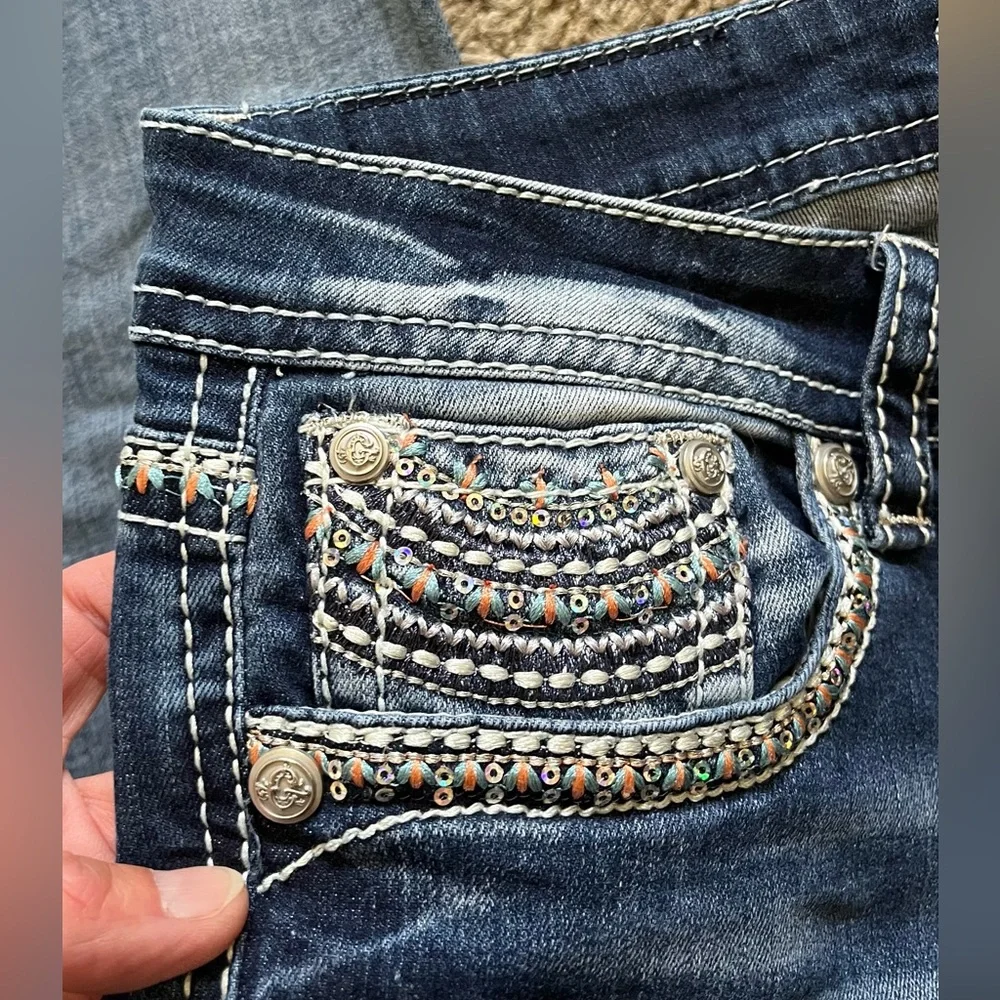 Grace in LA bootcut blue jeans with sequin and embroidery designs. Women’s 29